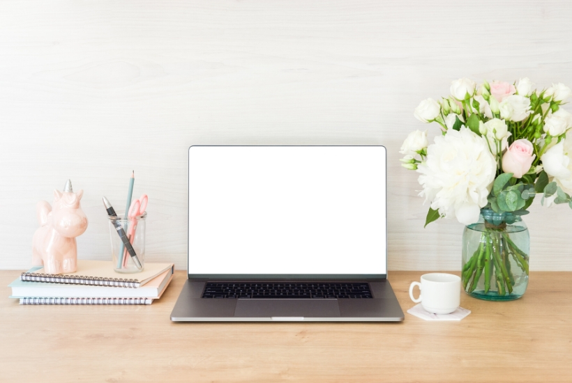 clean and organized desktop with notebooks, laptop, and vase of flowers