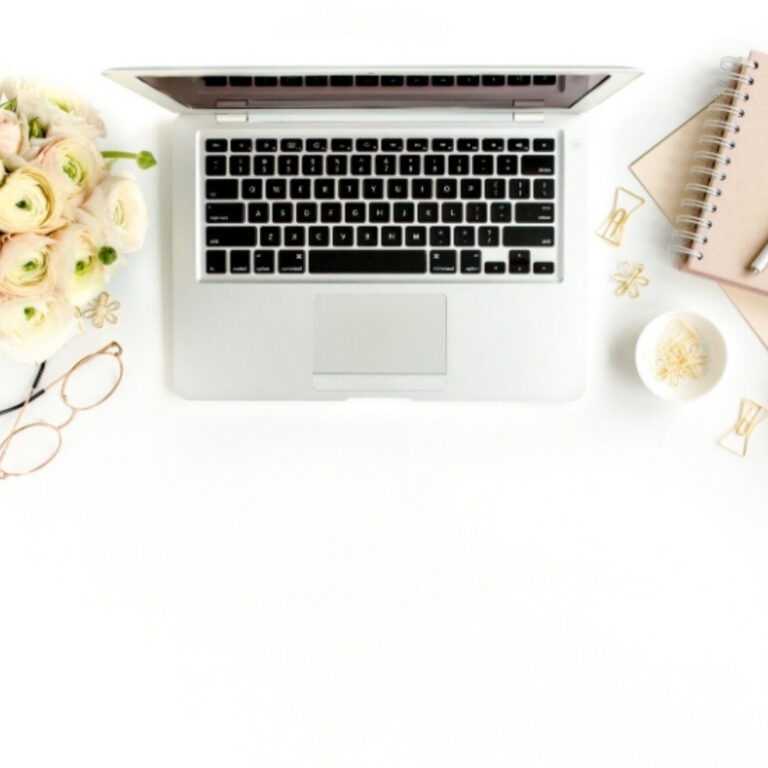 desktop with laptop, notebook, pen, and cup of coffee