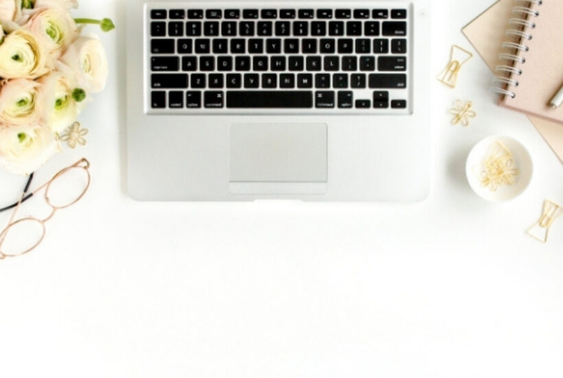 desktop with laptop, notebook, pen, and cup of coffee