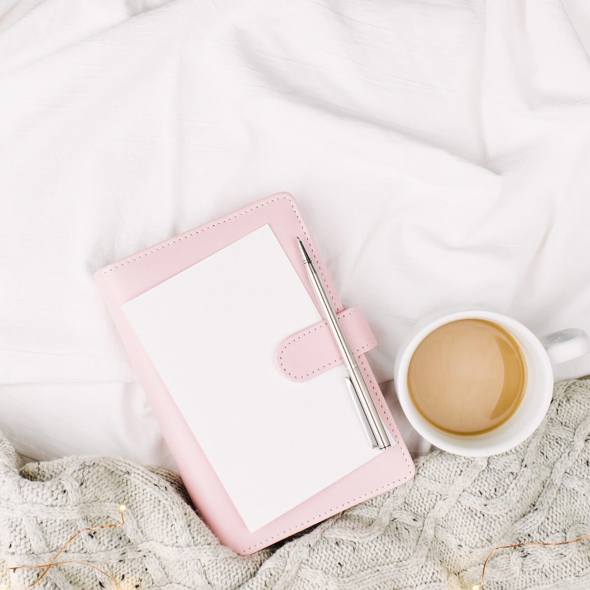 light pink planner with a white coffee mug filled with coffee