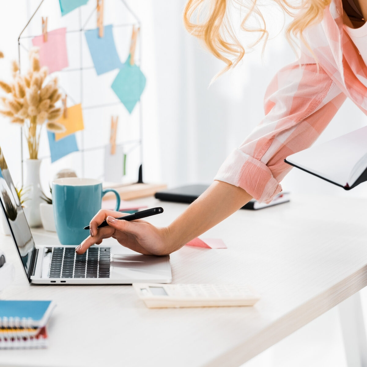 lady standing at desk and leaning to type on laptop