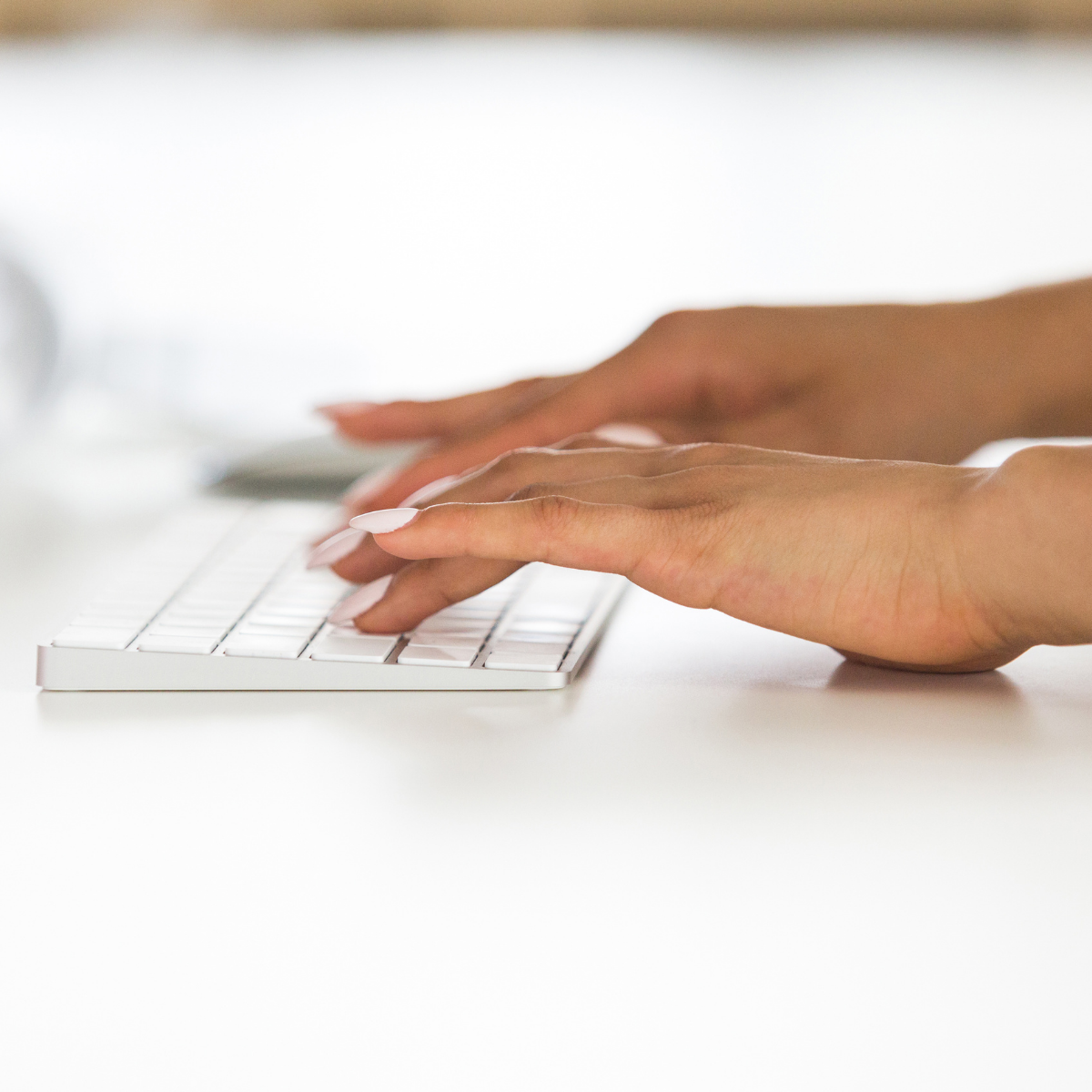 female typing on a white wireless keyboard